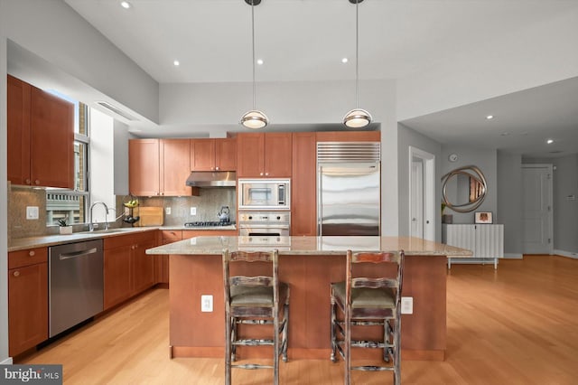 2425 L St NW Unit 623, Washington, DC 20037 - kitchen with built in appliances, under cabinet range hood, light wood-style flooring, a sink, and a kitchen island