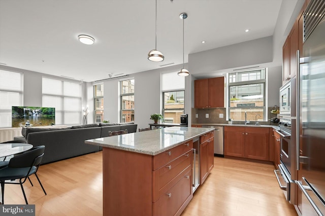 2425 L St NW Unit 623, Washington, DC 20037 - kitchen with built in appliances, light wood finished floors, light stone counters, a center island, and brown cabinets