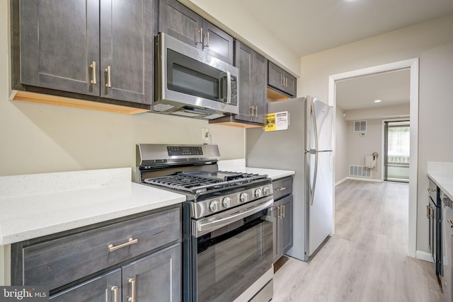 5241 W Running Brook Rd Unit 302, Columbia, MD 21044 - kitchen featuring appliances with stainless steel finishes, light wood-style floors, baseboards, dark brown cabinetry, and light stone countertops