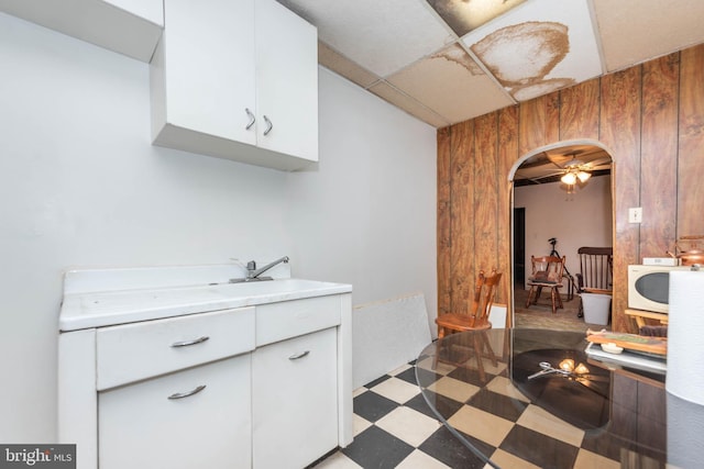 113 N Highland Ave, Baltimore, MD 21224 - kitchen with white microwave, white cabinets, a sink, arched walkways, and tile patterned floors
