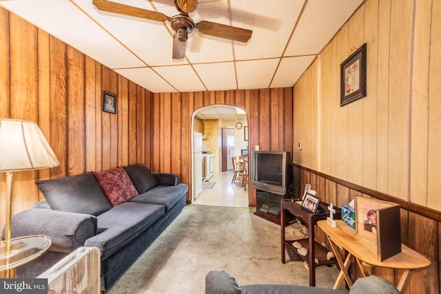 113 N Highland Ave, Baltimore, MD 21224 - living room featuring arched walkways, concrete floors, a ceiling fan, wooden walls, and a drop ceiling