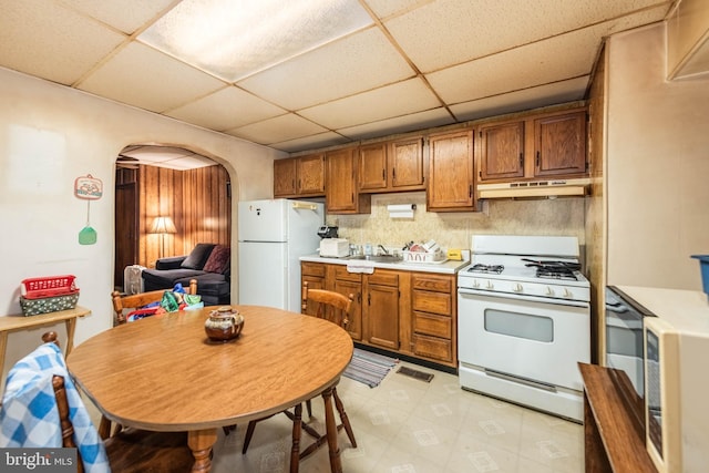 113 N Highland Ave, Baltimore, MD 21224 - kitchen with white appliances, arched walkways, under cabinet range hood, a paneled ceiling, and light countertops