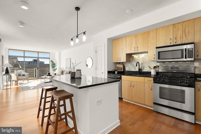 475 K St NW Unit 906, Washington, DC 20001 - kitchen with stainless steel appliances, light brown cabinets, a sink, light wood-style floors, and decorative backsplash