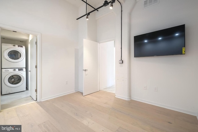 444 N 4th St Unit 415, Philadelphia, PA 19123 - unfurnished living room featuring stacked washer / drying machine, light wood-style flooring, a towering ceiling, and baseboards