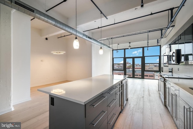 444 N 4th St Unit 415, Philadelphia, PA 19123 - kitchen with gray cabinetry, light wood finished floors, a center island, pendant lighting, and light countertops