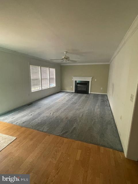 8 Love Creek Dr, Lewes, DE 19958 - unfurnished living room with ornamental molding, a ceiling fan, a fireplace, wood finished floors, and baseboards