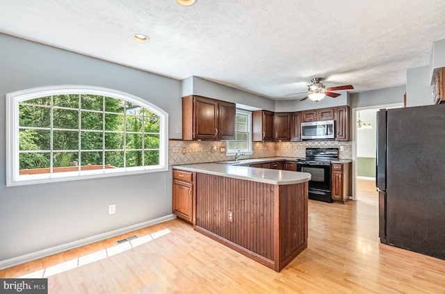 351 Point To Point Rd, Bel Air, MD 21015 - kitchen with black appliances, a peninsula, light wood-style flooring, tasteful backsplash, and a textured ceiling
