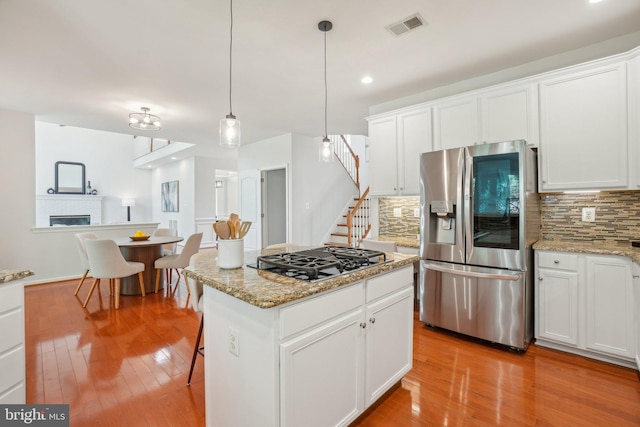 25487 Dabner Dr, Chantilly, VA 20152 - kitchen featuring stainless steel fridge with ice dispenser, black gas stovetop, tasteful backsplash, light wood finished floors, and white cabinetry