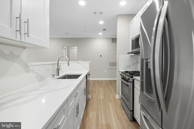 11345 Aristotle Dr Unit 6-311, Fairfax, VA 22030 - kitchen featuring appliances with stainless steel finishes, a sink, light wood-style floors, light stone countertops, and white cabinetry