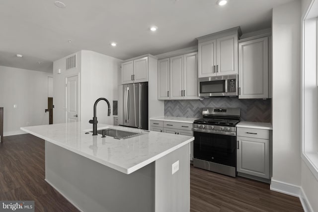 43294 Farringdon Sq, Broadlands, VA 20148 - kitchen with appliances with stainless steel finishes, a sink, decorative backsplash, gray cabinets, and a kitchen island with sink
