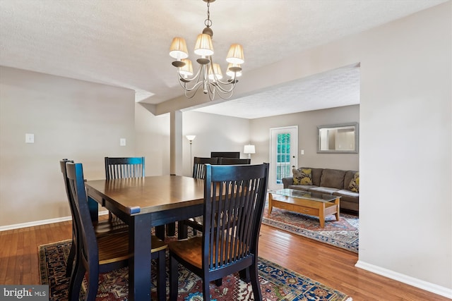 9175 Forest Lawn Ct, Springfield, VA 22152 - dining room featuring wood finished floors, a chandelier, a textured ceiling, and baseboards