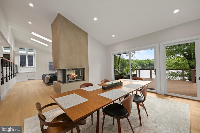 2201 Burgee Ct, Reston, VA 20191 - dining room with vaulted ceiling, a multi sided fireplace, light wood-type flooring, recessed lighting, and stairs