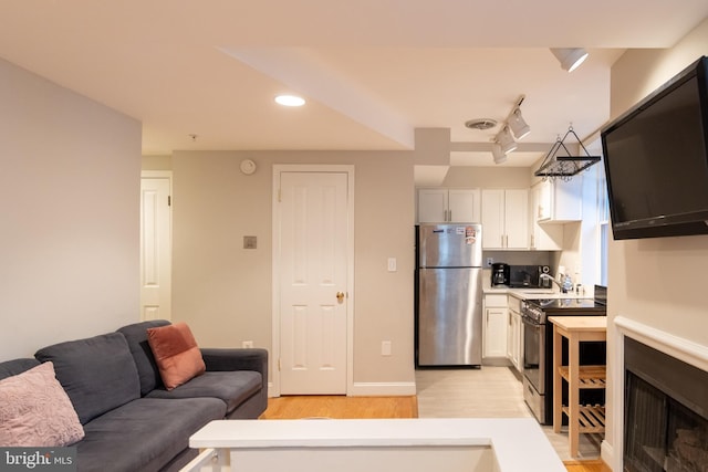 1731 Willard St NW Unit 102, Washington, DC 20009 - kitchen featuring freestanding refrigerator, electric range oven, light wood-style floors, light countertops, and white cabinetry