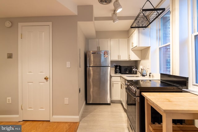1731 Willard St NW Unit 102, Washington, DC 20009 - kitchen with appliances with stainless steel finishes, light wood-style floors, white cabinets, light countertops, and baseboards