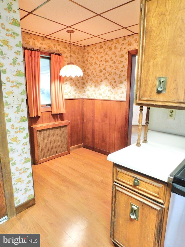 1216 23rd Ave, Altoona, PA 16601 - kitchen with wallpapered walls, a wainscoted wall, light wood-style flooring, brown cabinetry, and hanging light fixtures