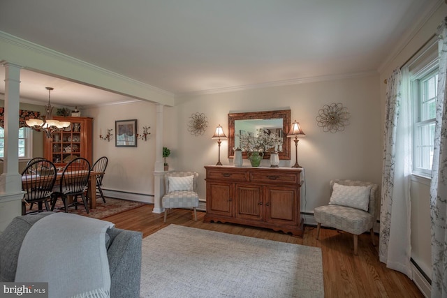 128 Cherry Ln, Doylestown, PA 18901 - living room featuring ornate columns, a baseboard heating unit, wood finished floors, ornamental molding, and a chandelier