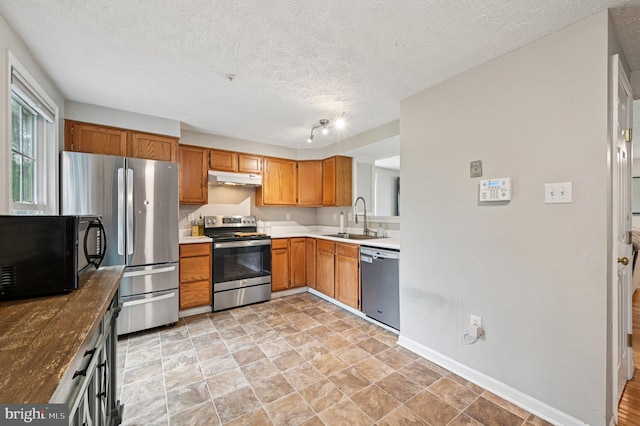 8924 Oxley Forest Ct, Laurel, MD 20723 - kitchen with appliances with stainless steel finishes, under cabinet range hood, a textured ceiling, brown cabinetry, and light countertops