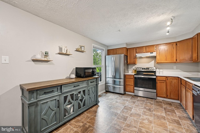 8924 Oxley Forest Ct, Laurel, MD 20723 - kitchen featuring appliances with stainless steel finishes, under cabinet range hood, a textured ceiling, light countertops, and brown cabinets