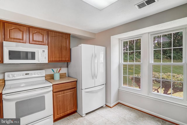 9147 Everett Ct, Springfield, VA 22152 - kitchen featuring white appliances, light countertops, brown cabinetry, and light tile patterned flooring