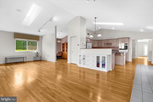 464 E Walnut St, Kutztown, PA 19530 - unfurnished living room with a skylight, track lighting, light wood-type flooring, baseboards, and high vaulted ceiling