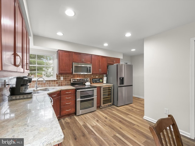 6290 Pinyon Pine Ct, Eldersburg, MD 21784 - kitchen featuring appliances with stainless steel finishes, beverage cooler, tasteful backsplash, light wood-style flooring, and light stone counters