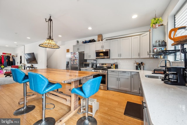 801 N 16th St Unit 1, Philadelphia, PA 19130 - kitchen featuring appliances with stainless steel finishes, a sink, gray cabinetry, decorative backsplash, and light wood-type flooring