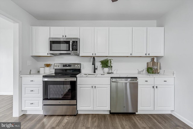 10 Taxi Way, Baltimore, MD 21220 - kitchen featuring appliances with stainless steel finishes, a sink, baseboards, dark wood-type flooring, and white cabinetry
