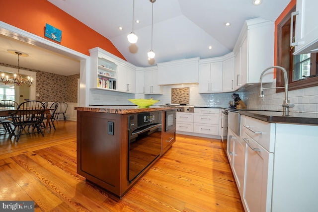 8317 High School Rd, Elkins Park, PA 19027 - kitchen with black oven, open shelves, vaulted ceiling, dark countertops, and white cabinets