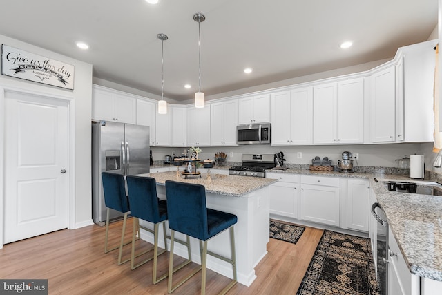 325 Hickory Ridge Cir, York, PA 17404 - kitchen with appliances with stainless steel finishes, white cabinetry, a center island, light wood finished floors, and a breakfast bar area
