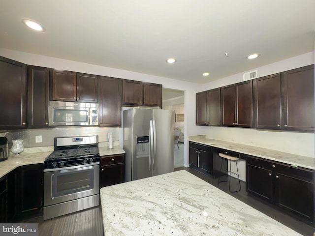 9506 Manor Oaks Vw, Upper Marlboro, MD 20772 - kitchen featuring appliances with stainless steel finishes, light stone counters, dark brown cabinets, recessed lighting, and wood finished floors