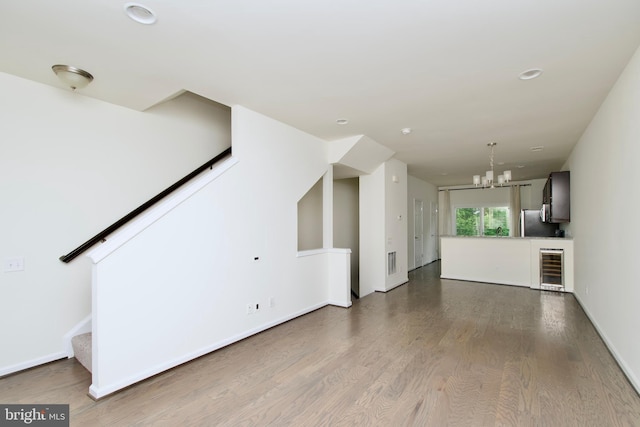 17023 Gibson Mill Rd, Dumfries, VA 22026 - unfurnished living room with beverage cooler, wood finished floors, stairway, a chandelier, and recessed lighting