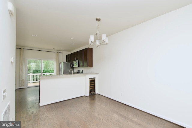 17023 Gibson Mill Rd, Dumfries, VA 22026 - kitchen with stainless steel appliances, beverage cooler, wood finished floors, dark brown cabinets, and a chandelier