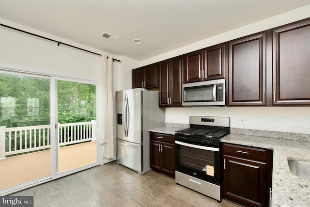 17023 Gibson Mill Rd, Dumfries, VA 22026 - kitchen with appliances with stainless steel finishes, light wood finished floors, dark brown cabinets, light stone countertops, and recessed lighting