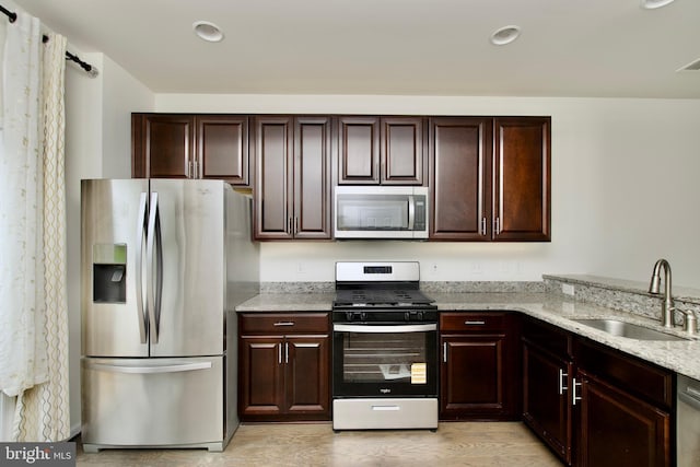 17023 Gibson Mill Rd, Dumfries, VA 22026 - kitchen featuring stainless steel appliances, a sink, light stone counters, light wood-type flooring, and dark brown cabinetry