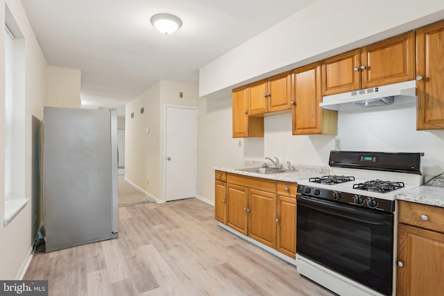 1018 W 7th St, Wilmington, DE 19805 - kitchen featuring gas range oven, under cabinet range hood, freestanding refrigerator, a sink, and light wood-style flooring