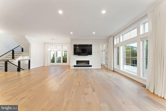 1554 Davidson Rd, Mclean, VA 22101 - unfurnished living room featuring ornamental molding, a warm lit fireplace, a chandelier, healthy amount of natural light, and light wood finished floors