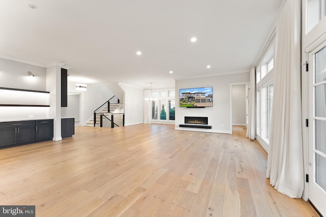 1554 Davidson Rd, Mclean, VA 22101 - unfurnished living room featuring ornamental molding, light wood-style floors, stairs, a warm lit fireplace, and recessed lighting