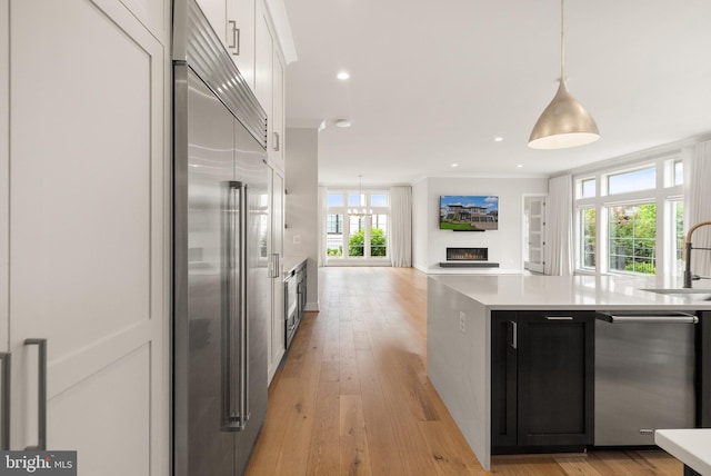 1554 Davidson Rd, Mclean, VA 22101 - kitchen with stainless steel appliances, a warm lit fireplace, light countertops, hanging light fixtures, and white cabinets