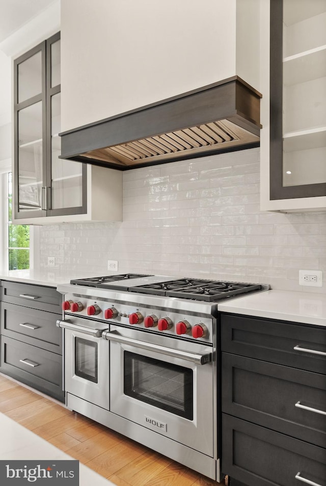 1554 Davidson Rd, Mclean, VA 22101 - kitchen with range with two ovens, wall chimney exhaust hood, light countertops, glass insert cabinets, and tasteful backsplash