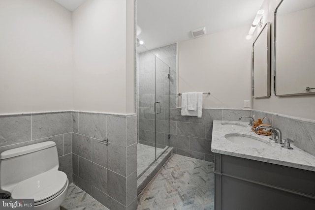 5376 28th St NW, Washington, DC 20015 - full bathroom with tile walls, toilet, double vanity, a stall shower, and wainscoting