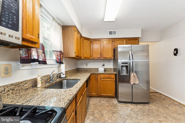4805 John St, Suitland, MD 20746 - kitchen with stainless steel appliances, a sink, brown cabinets, light stone countertops, and stone finish floors
