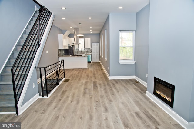 3137 Clifford St, Philadelphia, PA 19121 - unfurnished living room featuring stairs, baseboards, light wood finished floors, a glass covered fireplace, and recessed lighting