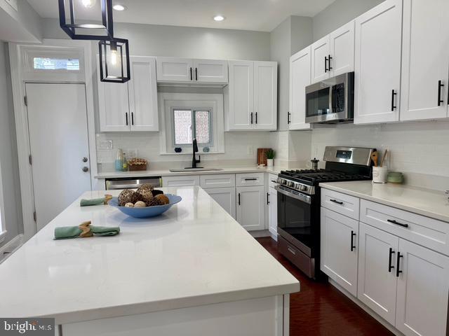 2621 E Monument St, Baltimore, MD 21205 - kitchen featuring stainless steel appliances, a sink, white cabinets, a kitchen island, and recessed lighting