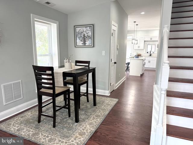2621 E Monument St, Baltimore, MD 21205 - dining room with stairs, dark wood-type flooring, and baseboards