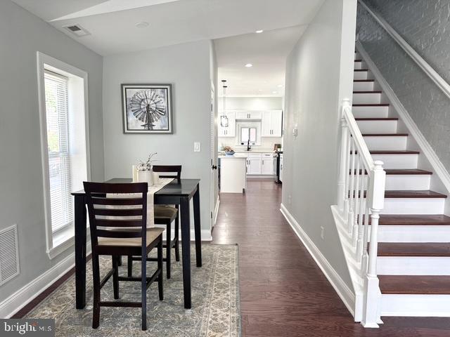 2621 E Monument St, Baltimore, MD 21205 - dining space featuring stairway, dark wood finished floors, and baseboards