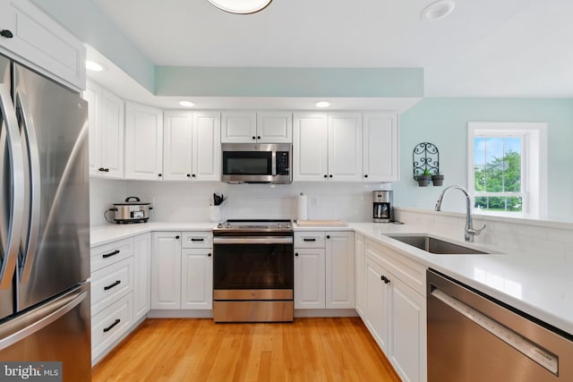 201 Pondview Ct, Chestertown, MD 21620 - kitchen with stainless steel appliances, a sink, white cabinetry, tasteful backsplash, and light wood-style flooring