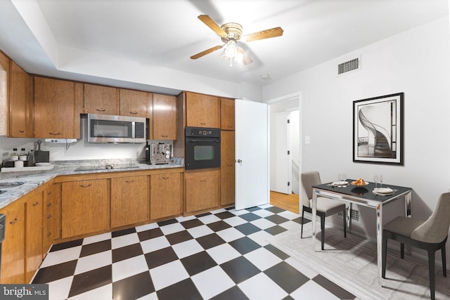 4503 Poppe Pl, Temple Hills, MD 20748 - kitchen with black appliances, tile patterned floors, ceiling fan, and brown cabinetry