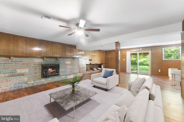 4503 Poppe Pl, Temple Hills, MD 20748 - living room with light wood-type flooring, a stone fireplace, wooden walls, and ceiling fan