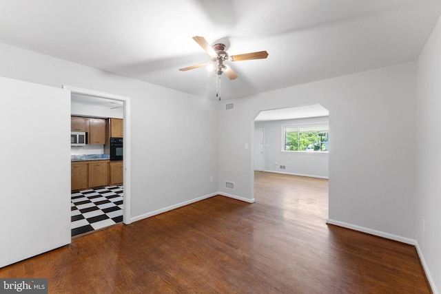 4503 Poppe Pl, Temple Hills, MD 20748 - empty room with arched walkways, ceiling fan, dark wood-style floors, and baseboards