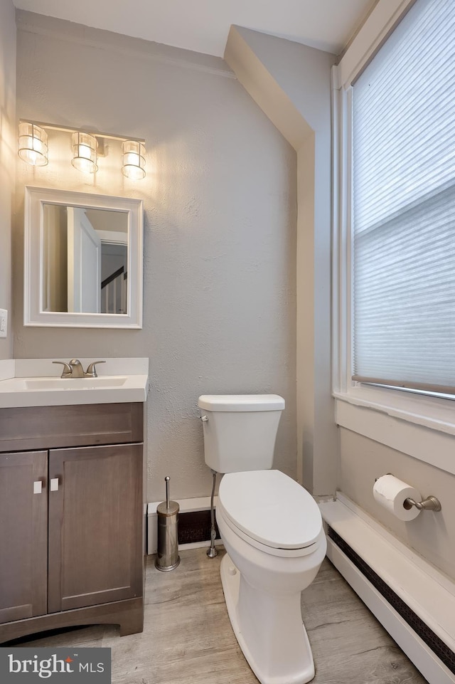 114 Walnut St, Columbia, PA 17512 - half bath featuring baseboard heating, toilet, vanity, wood finished floors, and baseboards